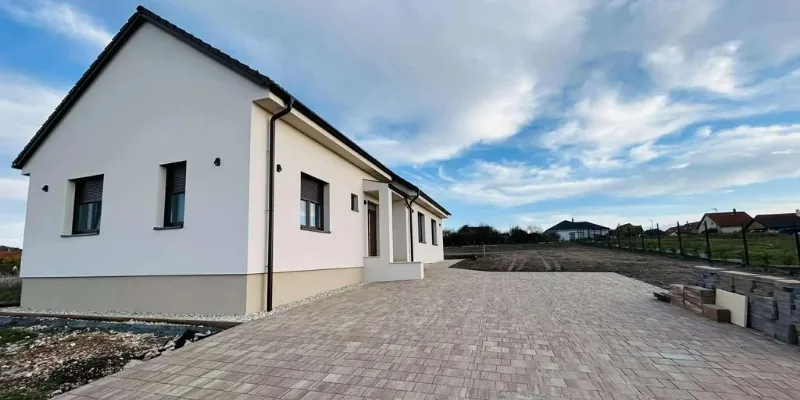 Panorámás családi ház szerkezetkész nappalija nagy üvegfelületekkel és vakolt falakkal a Bakony és a Balaton-felvidék találkozásánál.