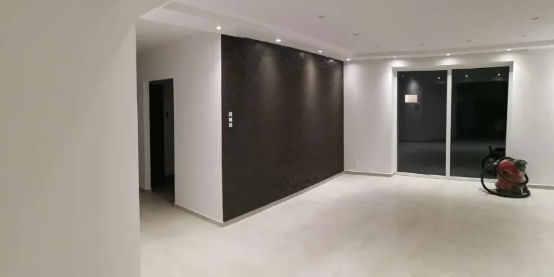 Készre festett, modern nappali belső tere spot világítással és nagy üvegfelületekkel, egy RB-Bau által épített házban.